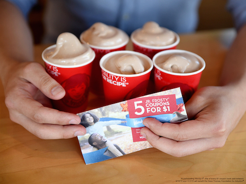 A person holding cups of Frostys and Frosty coupons. 